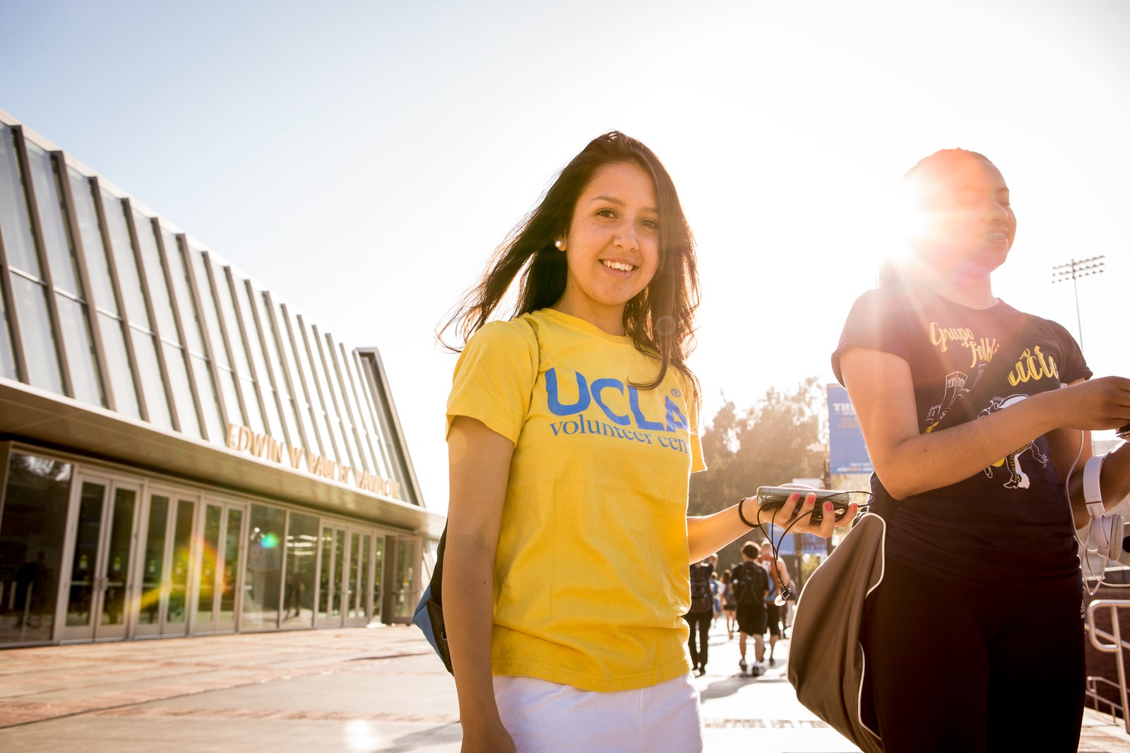 Two students pause on Bruin Walk near the north entrance to Pauley Pavilion. The student at left wears a UCLA Volunteer Center shirt.