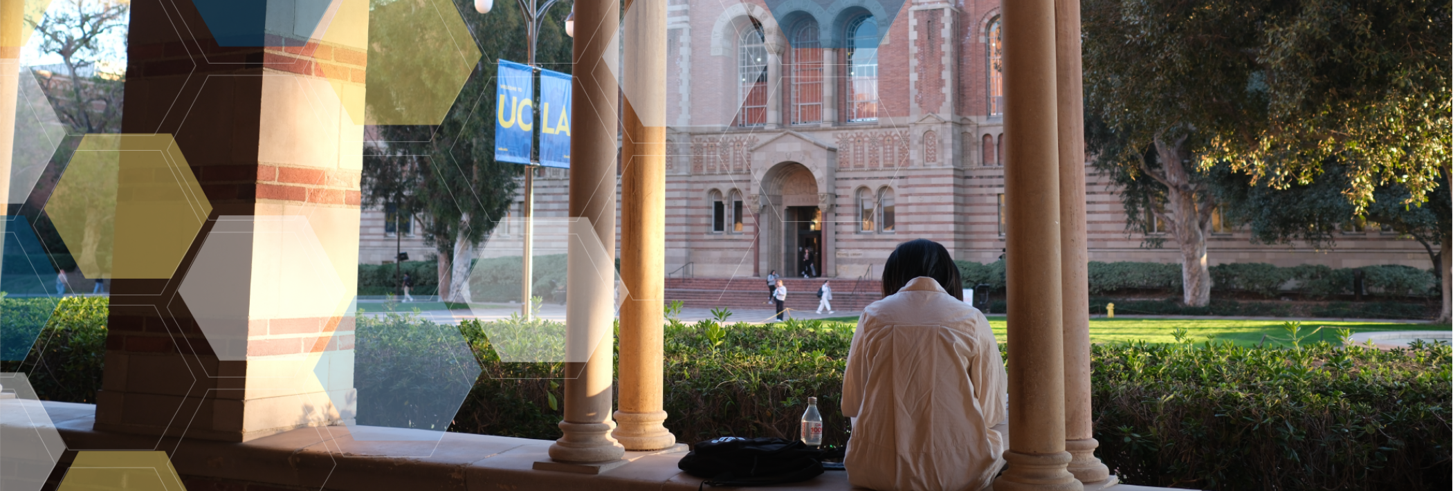 A student sits in the Royce breezeway overlooking Powell Library with blue, yellow, and white molecule overlay